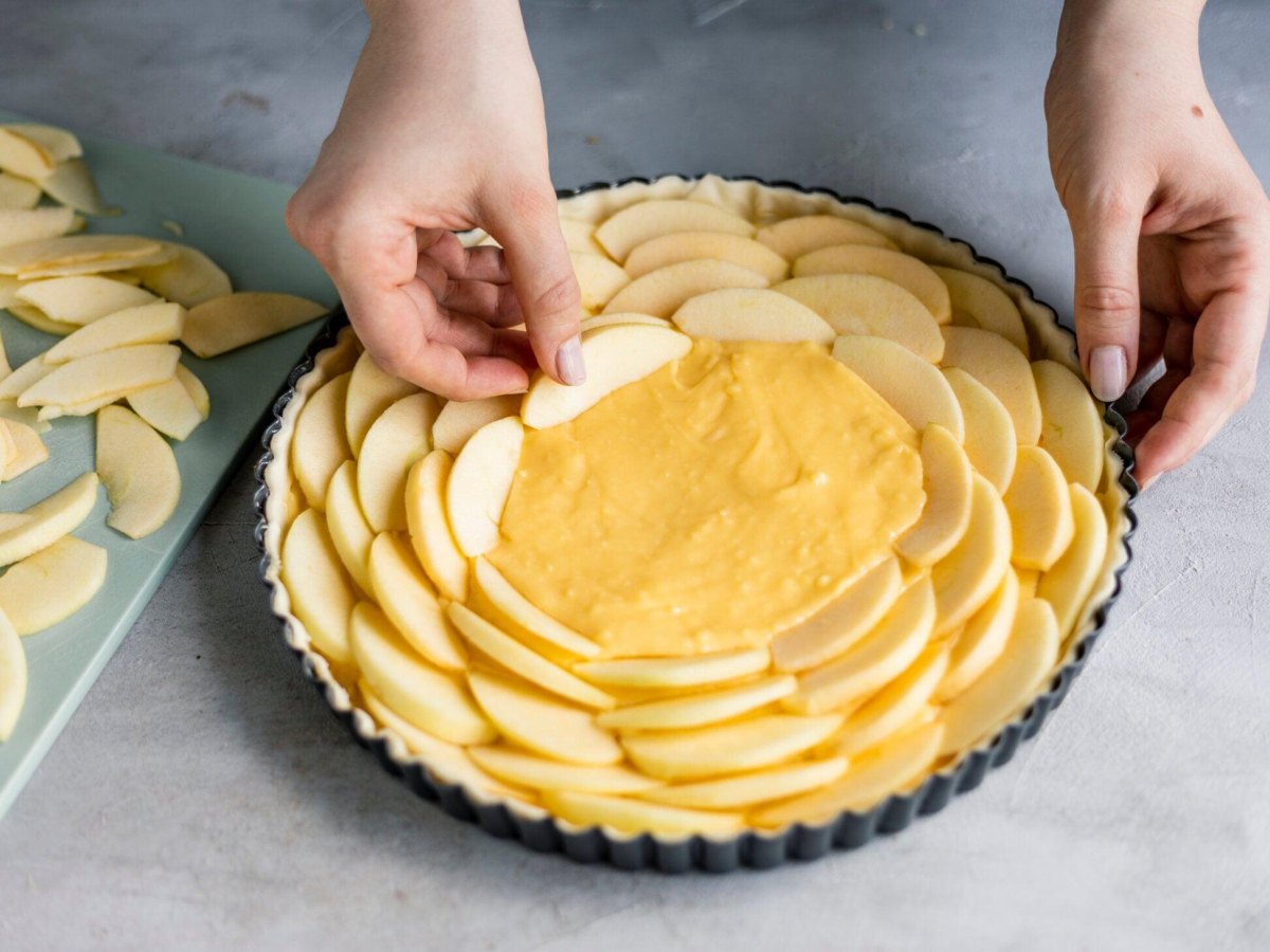 Apfelkuchen mit Vanillepudding mit dekorativ belegten Apfelscheiben