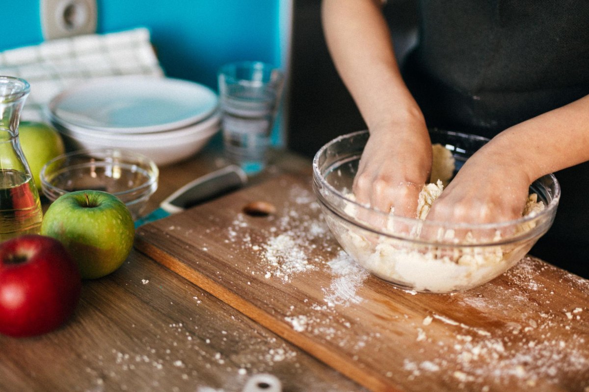 Apfelkuchen mit Vanillepudding Teigzubereitung mit Händen und frischen Zutaten